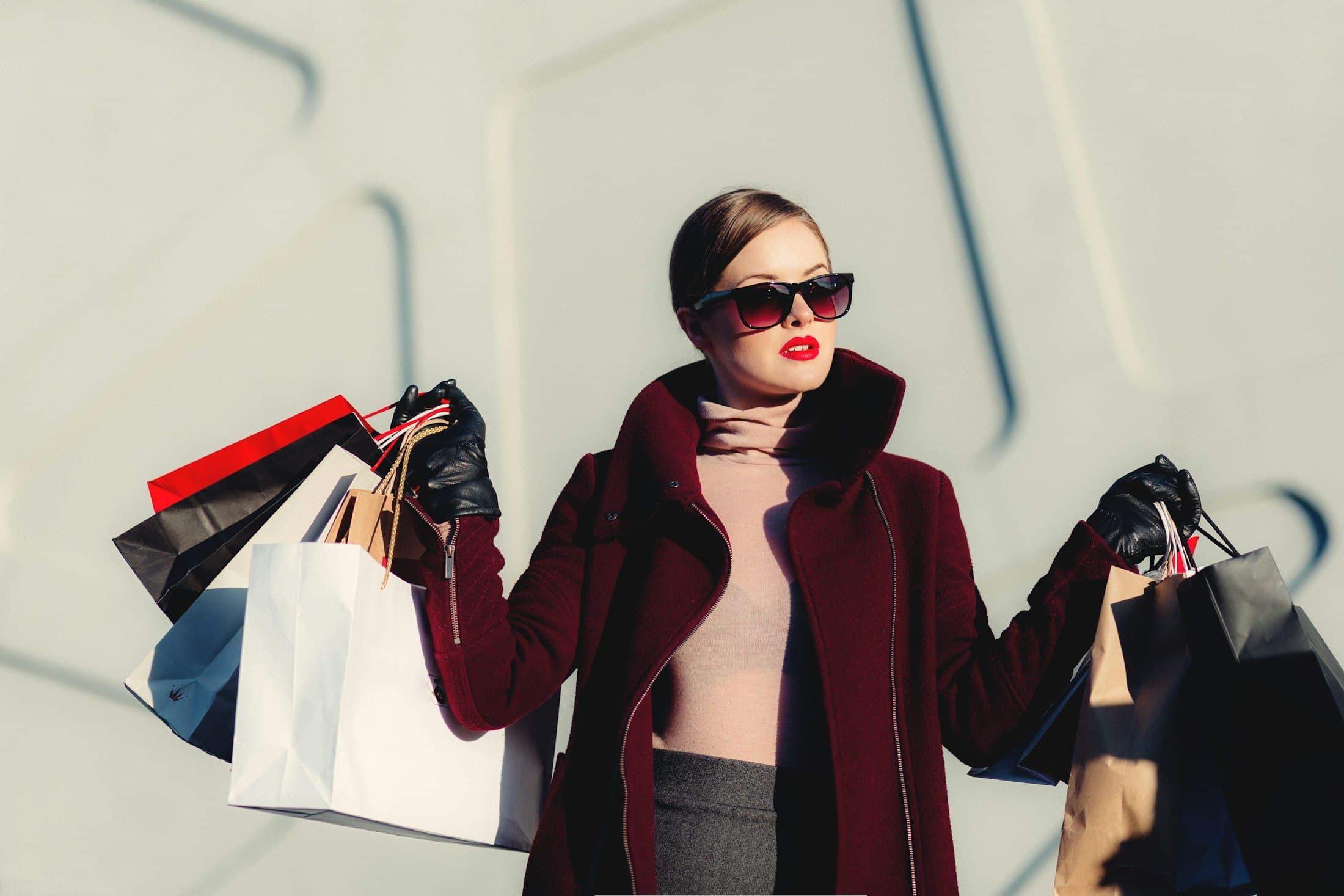 Compradora con bolsas de tienda sosteniendo lentes de sol